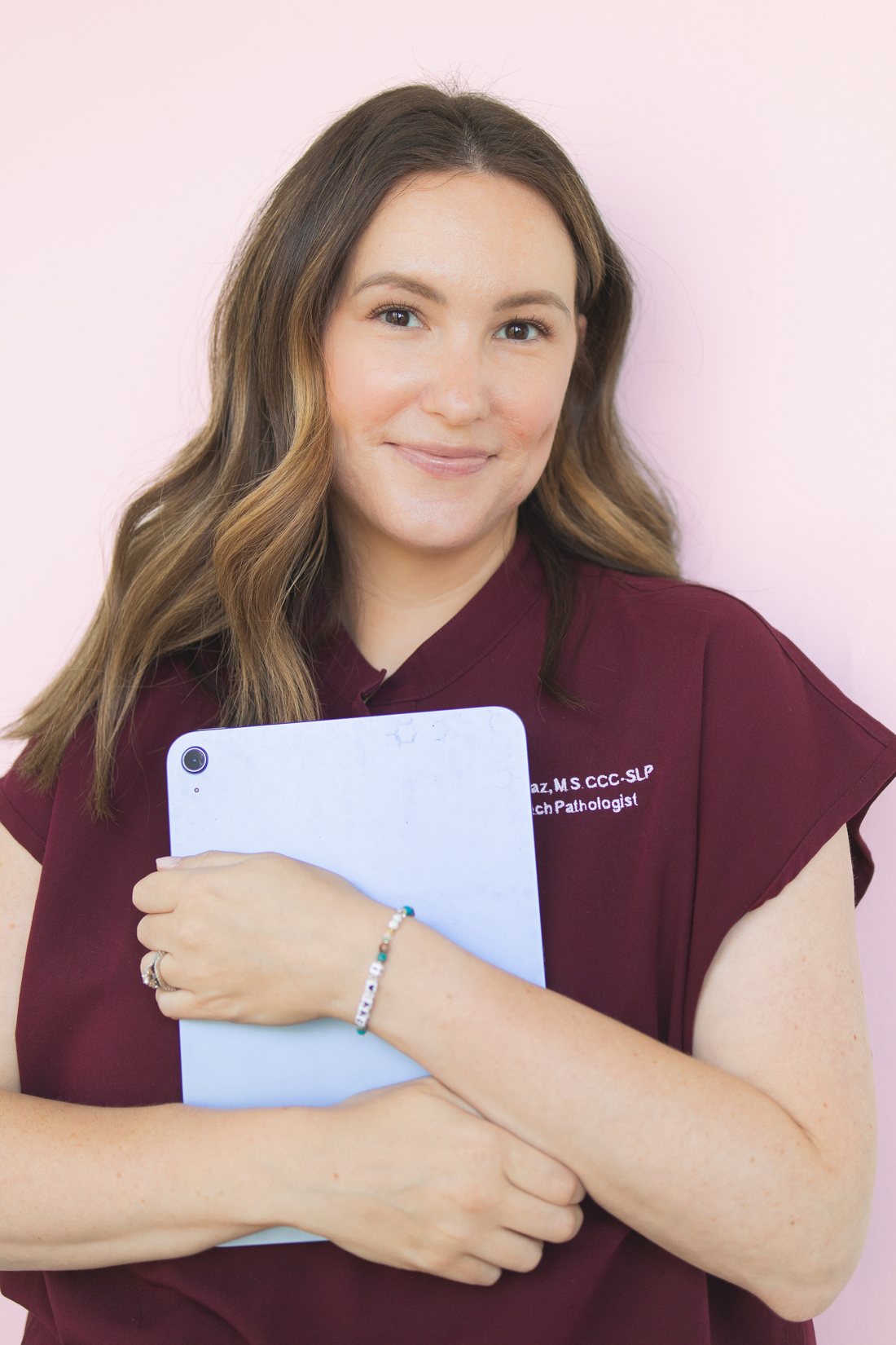 Emily Diaz, M.S., CCC-SLP, smiling and holding an iPad